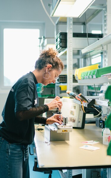 A Jossi employee assembles a mechanical assembly at a modern production workstation. The scene highlights careful craftsmanship and the precise manufacturing of industrial automation solutions.