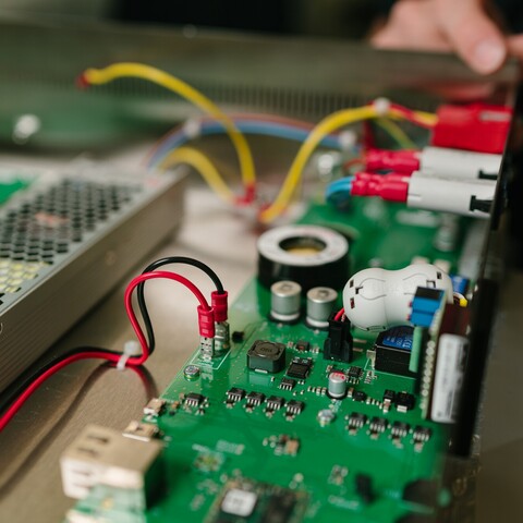 Nahaufnahme einer elektronischen Baugruppe einer Jossi-Automatisierungslösung mit Leiterplatte, Netzteil und Verkabelung. Die Aufnahme zeigt die hochwertige Steuerungselektronik und den präzisen Aufbau der Anlage.