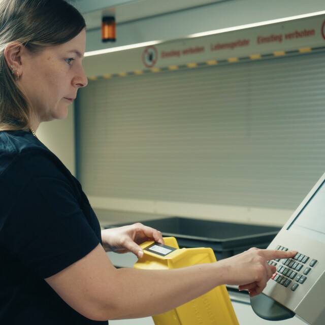 Eine Jossi-Mitarbeiterin bedient das Steuerungspanel einer automatisierten Produktionsanlage. Die Szene zeigt die Überwachung und Steuerung industrieller Fertigungsprozesse.