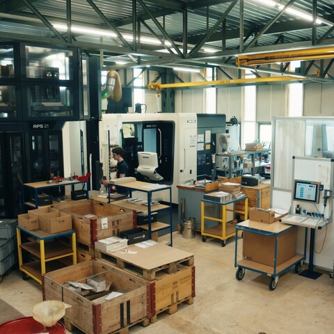 View of the Jossi production facility featuring modern machining centers, assembly workstations, and material staging areas. The scene showcases the industrial manufacturing of automation solutions.