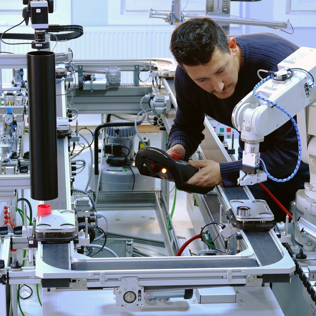 Mann in einem Labor arbeitet an Mechatronik als Symbol für Jossi Automatisierungstechnik