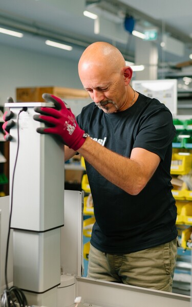 A Jossi employee assembles a module of an industrial automation solution at a modern production workstation. The scene highlights precise assembly work and the careful manufacturing of high-quality system components.