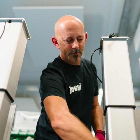 A Jossi employee assembles an industrial automation solution at a production workstation. The scene highlights precise assembly work and the manufacturing of high-quality system components.