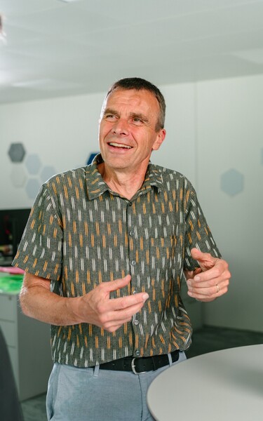 Three Jossi employees discuss the development and functionality of a technical prototype. The scene conveys collaboration, knowledge sharing, and joint product development within the company.