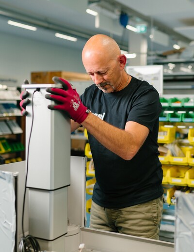 Ein Jossi-Mitarbeiter montiert eine Baugruppe einer industriellen Automatisierungslösung an einem modernen Montagearbeitsplatz. Die Szene zeigt präzise Montagearbeiten und die sorgfältige Fertigung hochwertiger Anlagenkomponenten.