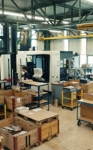 View of the Jossi production facility featuring modern CNC machining centers, assembly workstations, and organized material staging. The scene highlights the manufacturing of high-quality components and industrial automation solutions in a modern producti