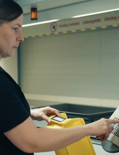 Eine Jossi-Mitarbeiterin bedient das Steuerungspanel einer automatisierten Produktionsanlage. Die Szene zeigt die Überwachung und Steuerung industrieller Fertigungsprozesse.
